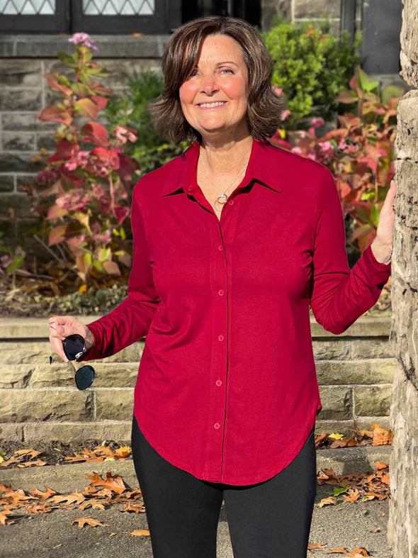 Miik founder Donna (5'6", small) smiling wearing Miik's Susan button up dress shirt in red wine along with a black pant