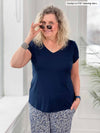 Miik model Carolyn (5'10", large) smiling wearing Miik's Sutton v-neck classic tee in navy along with a printed pant and holding her sunglasses on her face 