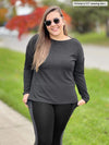 Woman standing on the sidewalk wearing Miik's Swansen drop shoulder buttoned top in grey with black and grey leggings