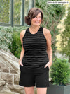 Miik founder Donna (5'6", small) smiling and looking away wearing Miik's Teanna high neck tank top in black wide pinstripe with a black shorts 