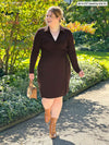 Miik model Bri (5'5", medium) walking and smiling wearing Miik's Tierney collared faux wrap dress in dark chocolate
