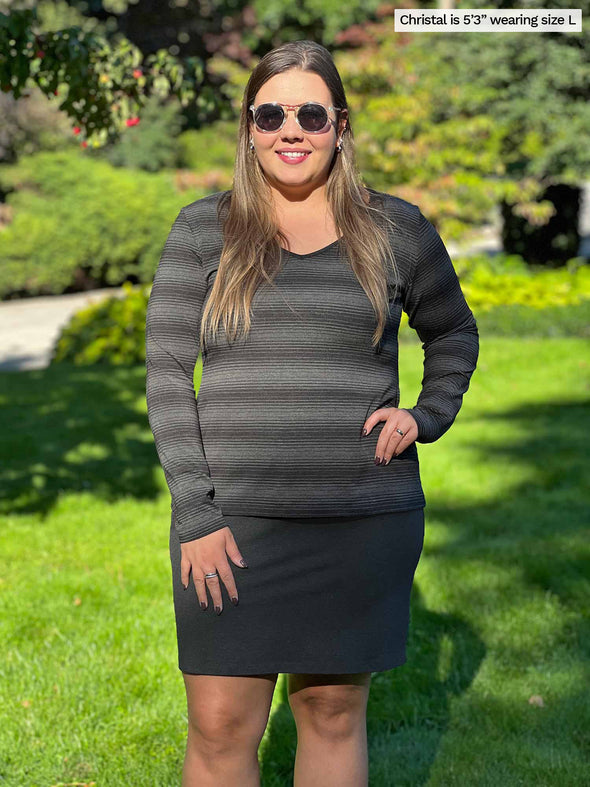 Woman standing on grass wearing Miik's Tray long sleeve striped tee in charcoal stripe with a charcoal skirt