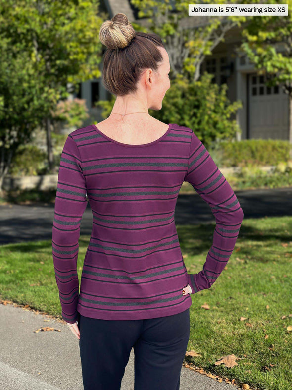 Miik model Johanna, size XS, showing the back of the Tray long sleeve striped reversible tee while wearing navy pants.