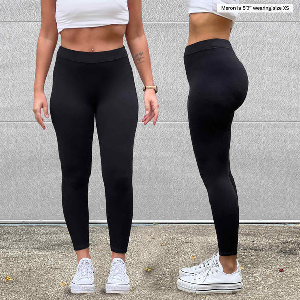 Miik model Meron (5'3", xsmall) wearing Miik's Tyson mid-rise fleece legging in black. The image is showing a close up front and side of the legging 
