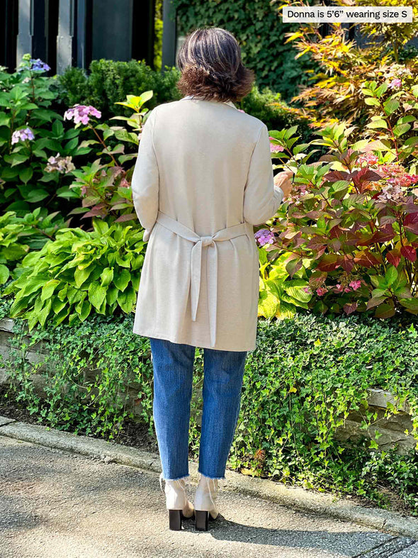 Miik's founder Donna (5'6", small) standing with her back towards the camera showing the back of Miik's Vula belted cardigan with pockets in camel melange 