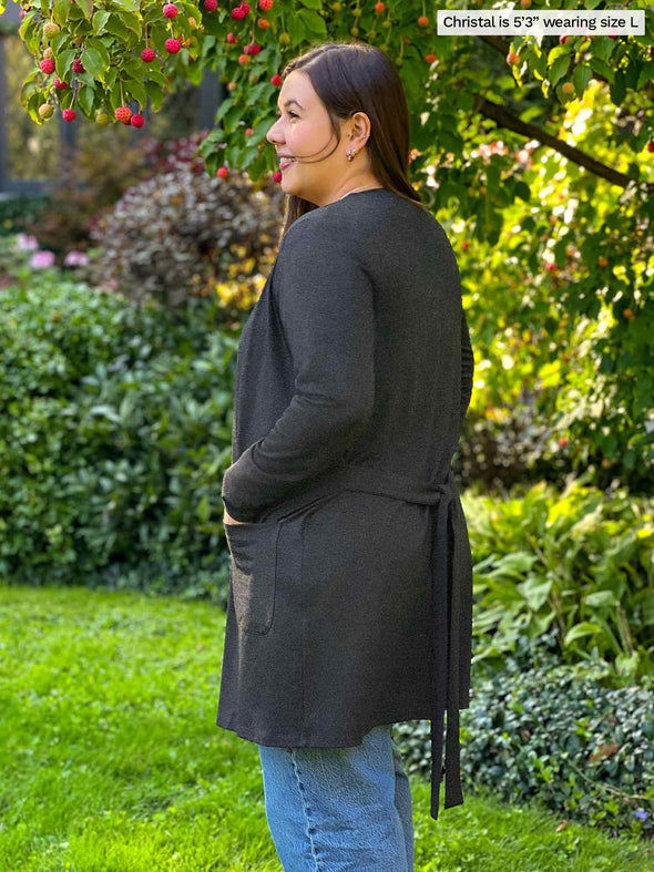 Miik model Christal (5'3", large) showing the back/side of Miik's Vula belted cardigan with pockets in charcoal 