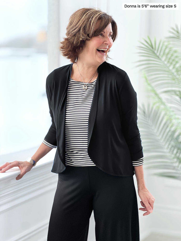 Miik founder Donna (5'6", small) laughing and looking away wearing Miik's Wesley cropped cardigan in black with a pant in the same colour and a striped black and white tee 
