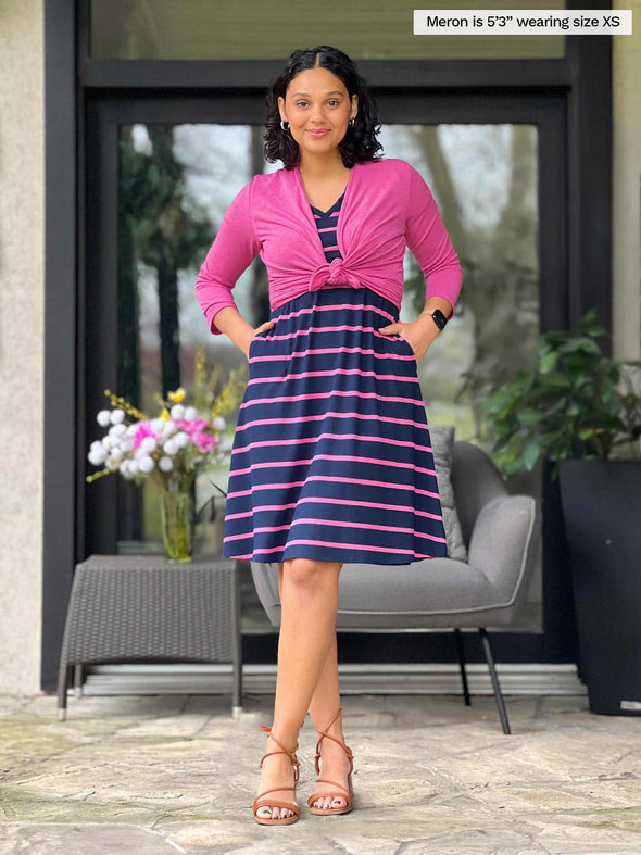 Miik model Meron (5'3", xsmall) wearing a striped navy/pink t-shirt dress with pockets along with Miik's Wesley cropped cardigan in pink knotted 