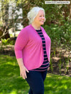 Miik model Colleen (5'3", xxlarge) standing sideway and smiling wearing a navy/pink striped tee, a navy legging and Miik's Wesley cropped cardigan in pretty in pink