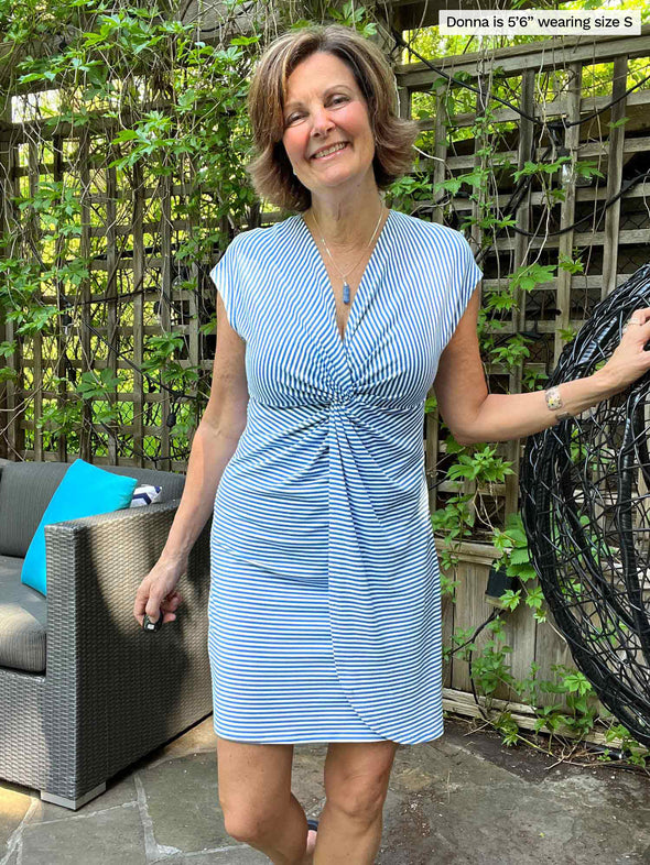 Woman standing in front of a trellis and couch while wearing Miik's Wesson 3-in-1 cover up dress in blue stripe