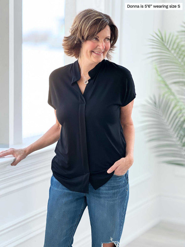 Miik founder Donna (5'6", small) smiling and looking away wearing Miik's Yasmina band collar blouse in black untucked with jeans 