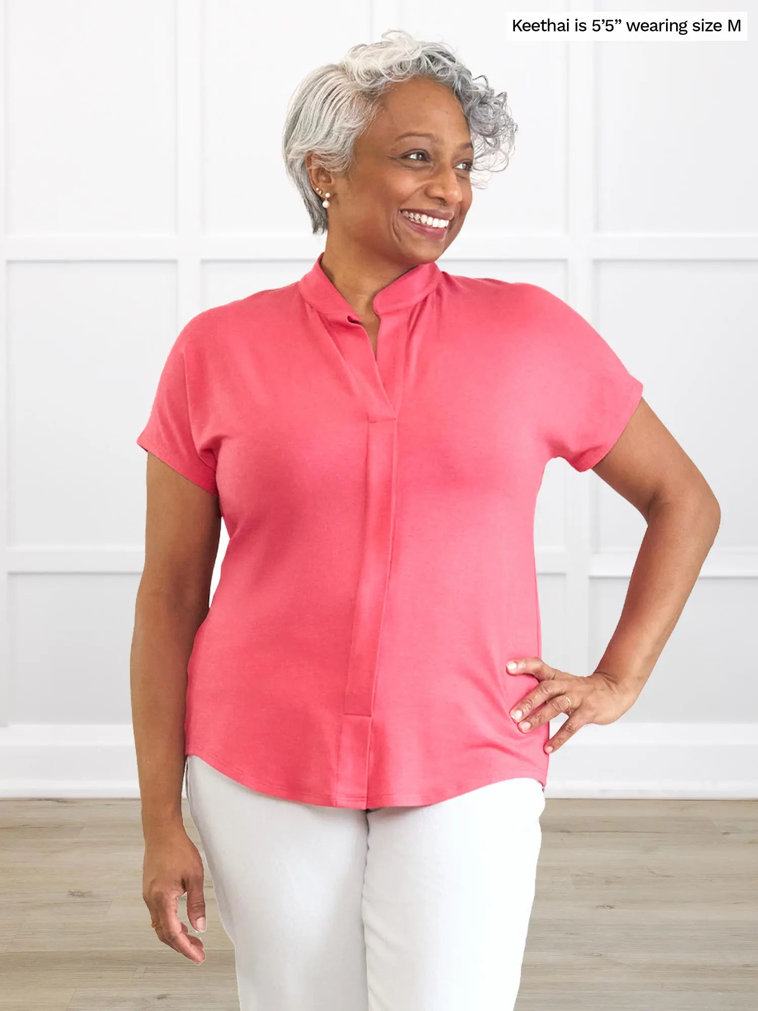 Woman wearing a pink shirt and white pants against a white background 