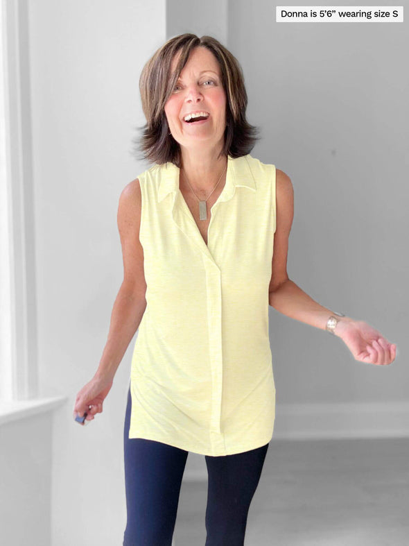Woman standing in front of a wall wearing Miik's Zuraidah dressy tunic top in yellow with navy leggings.
