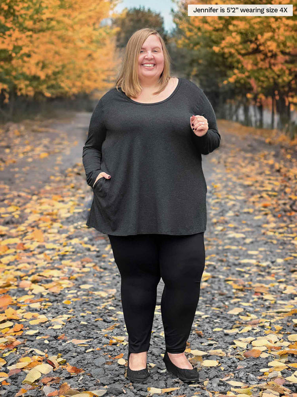 Miik model plus size Jen (5'2", size 4x) smiling wearing a black legging along with Miik's Zuri long sleeve pocket tunic in charcoal with a high waited legging in black