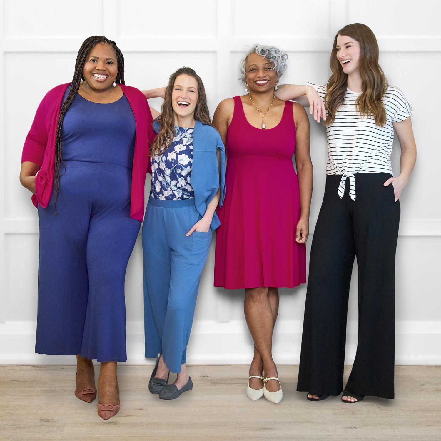Four women posing together against a white wall