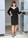 Woman smiling while opening a door wearing Miik's Adelaide collared faux layered dress in black and boots