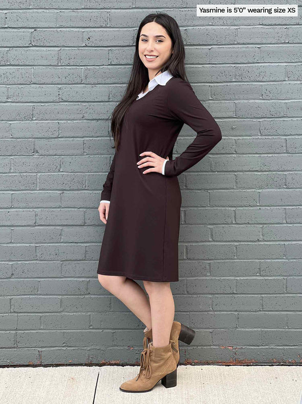 Woman standing sideway in front of a brick wall wearing Miik's Adelaide collared faux layered dress in dark chocolate 