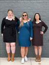 Three women standing in front of a brick wall wearing Miik's Adelaide collared faux layered dress in three different colours: black, teal and dark chocolate 