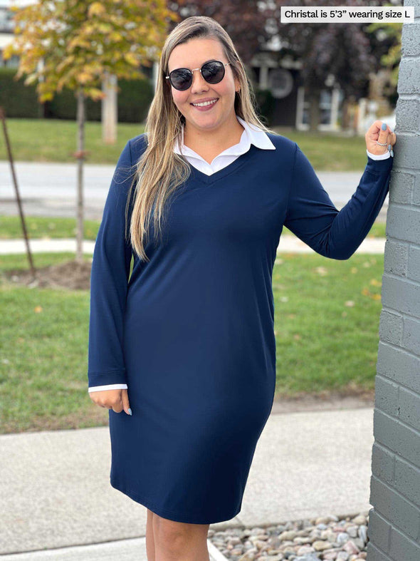 Woman standing next to a brick wall wearing Miik's Adelaide collared faux layered dress in navy and sunglasses