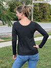 Woman standing in nature with her back towards the camera showing the back of Miik's Albany contrast long sleeve top in charcoal and jeans