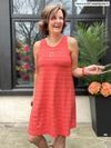 Miik founder Donna wearing the a-line swing dress Aubrey in an orange pinstripe while smiling outside holding sunglasses.