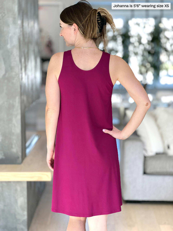 Miik model Johanna (five feet six, size extra small) standing with her back towards the camera showing the back of Miik's Aubrey reversible swing dress in ruby