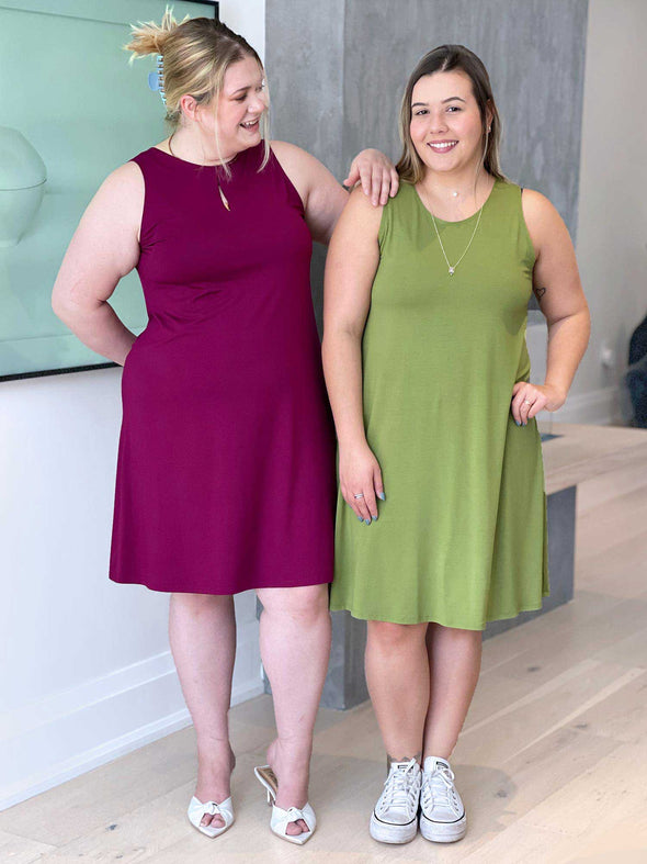 Miik models Christal (five foot three, size large) and Bri (five foot five, size extra large) standing next to each other and smiling wearing Miik's Aubrey reversible swing dress in ruby and green moss