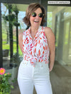 Woman standing outside while wearing Miik's Avy button-up dressy tunic top tied in sunset leaf with white pants