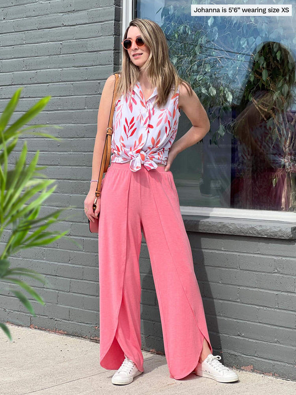 Woman standing in front of a window looking away wearing Miik's Avy button-up dressy tunic top in pink leaf pattern tied with matching colour pants.