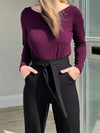 Close up of Miik's Blair bamboo tie waist belt in black wrapped around a woman's waist wearing a burgundy top with black pants.