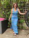 Woman smilling and standing in front of trellis wearing Miik's brodie racerback tank maxi dress in blue stripe color