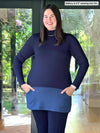 Woman standing in a backyard wearing Miik's Brooklin mock neck pocket tunic in navy/navy melange with a matching colour legging in navy