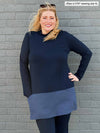 Woman standing in front of a brick wall wearing Brooklin mock neck pocket tunic in navy/navy melange with navy legging