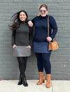 Two women standing in front of a brick wall smiling wearing Miik's Brooklin mock neck pocket tunic in charcoal/granite melange and navy/navy melange