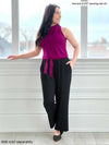 Miik model Yasmine (five feet tall, size extra small, petite) standing in front of a window looking away wearing Miik's Easton pocket capri with a Blair belt in ruby with a mock neck tank in the same colour