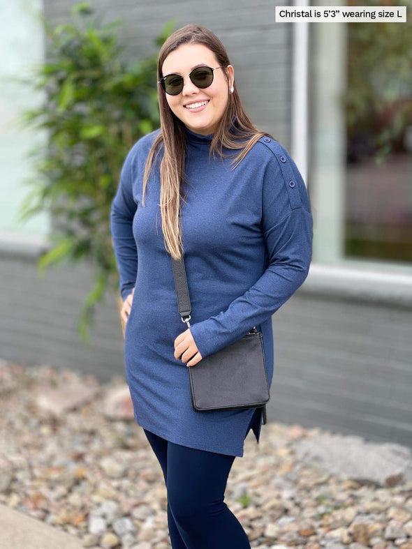 Woman standing in a sidewalk smiling while wearing Miik's Fergie buttoned long sleeve tunic in navy melange with navy legging and a crossbody purse