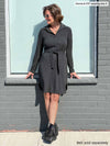 Woman leaning on a window wearing Miik's Finian collared shirt dress in grey with a matching belt.