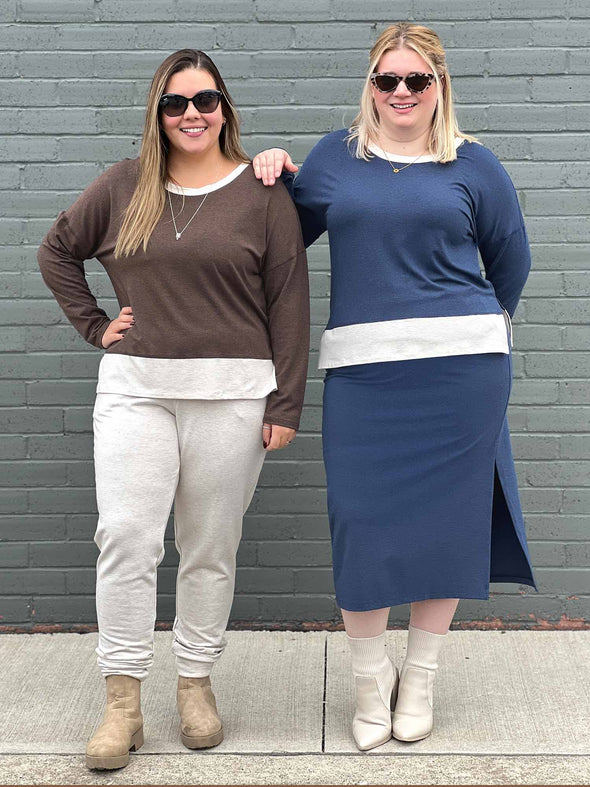 Two women standing in front of a brick wall wearing Geneva two-tone crew neck top in two different colours: chocolate melange/oatmeal and navy melange/oatmeal