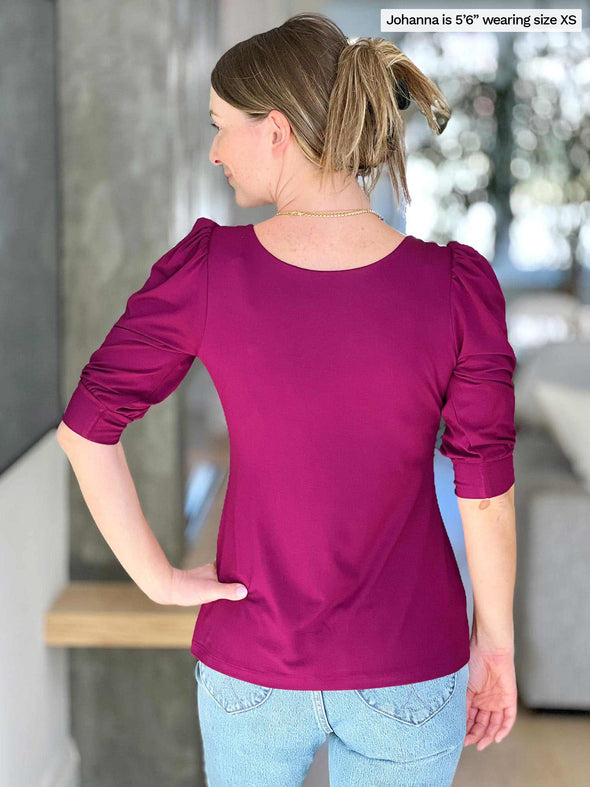 Woman standing with her back towards the camera showing the back of Miik's Gigi reversible puff sleeve blouse
