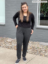 Woman standing outside on a sidewalk wearing Miik's Henley lounge jogger in charcoal with a long sleeve top in black