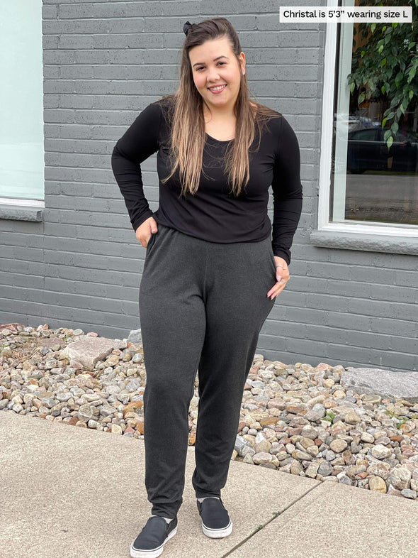 Woman standing outside on a sidewalk wearing Miik's Henley lounge jogger in charcoal with a long sleeve top in black