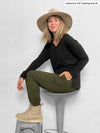 Woman siting sideway in a stool wearing Miik's Henley lounge jogger in sage melange with a black top