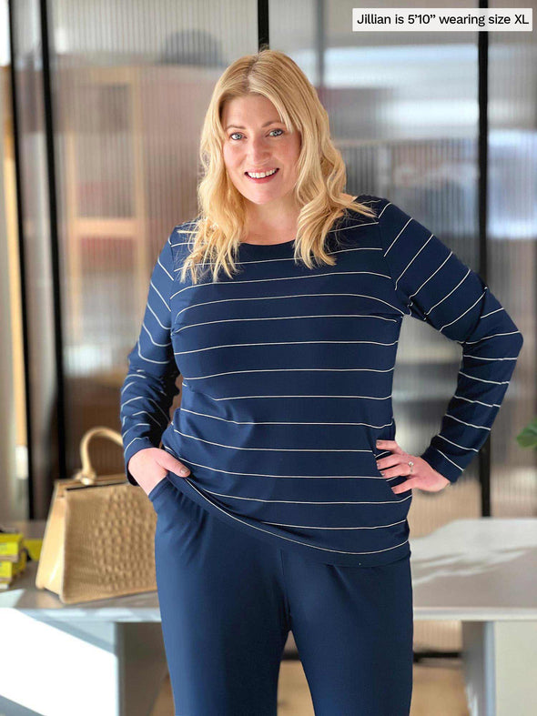 Woman standing in an office wearing Miik's Hilden ballet top in navy pinstripe along with a navy pant