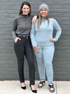 Two women standing in front of a brick wall both wearing Miik's India reversible fleece funnel neck sweater, one is wearing in mist melange and the other granite melange