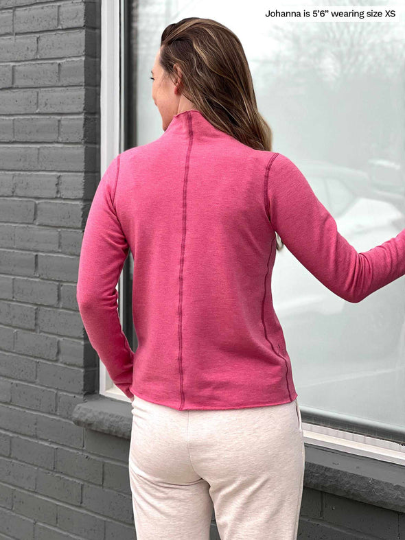 Woman standing with her back towards the camera showing the back of Miik's India reversible fleece funnel neck sweater in pink pomegranate