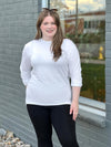 Woman standing next to a building wearing Miik's Jamie round neck long-sleeve in white with black leggings.