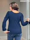 Woman standing with her back towards the camera showing the back of Miik's Janette top in navy