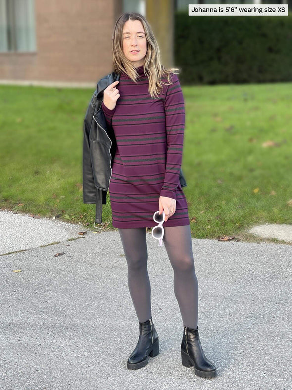 Woman standing on a sidewalk wearing Miik's Jordanna turtleneck tunic in port melange stripe with a leather jacket on her shoulders