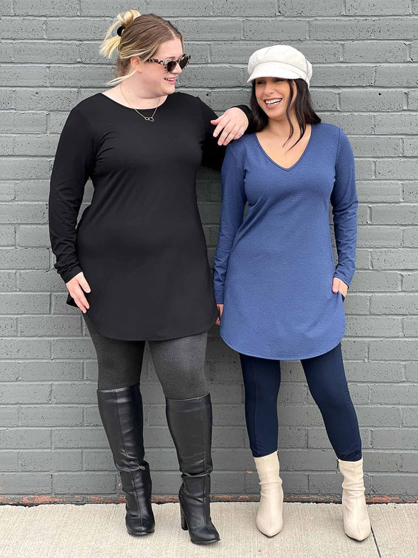 Two women standing next to each other wearing Miik's Juno reversible long sleeve tunic in black and navy melange with leggings. 