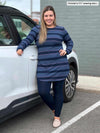 Woman smiling while leaning against a car wearing Miik's Juno reversible tunic in navy jewel tone stripe with legging in navy